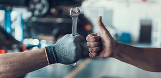 Employé d’atelier montrant un pouce levé – conseils sur pneus auto, pneus moto, montage et entretien